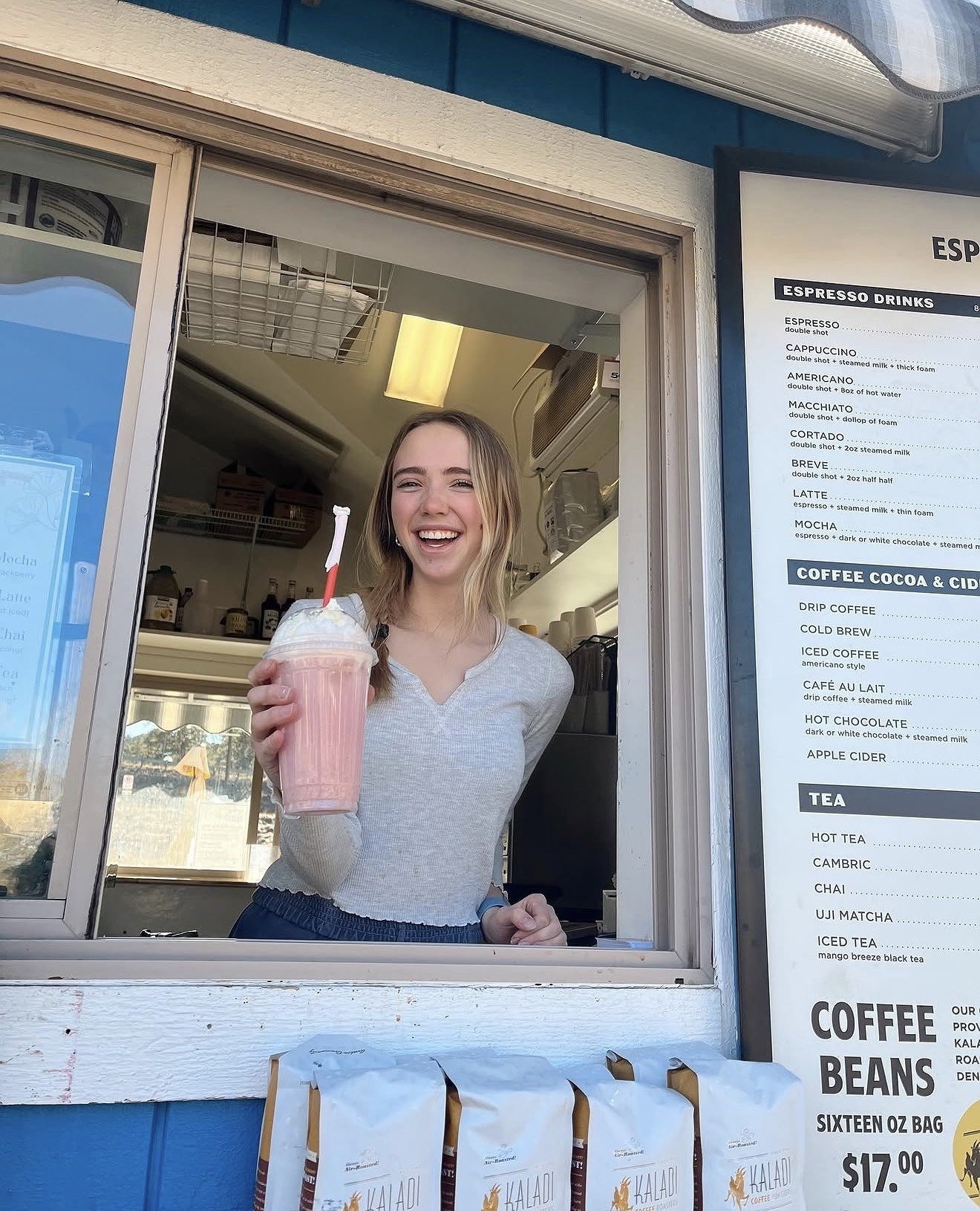 Barista at the window holding a strawberry blended drink